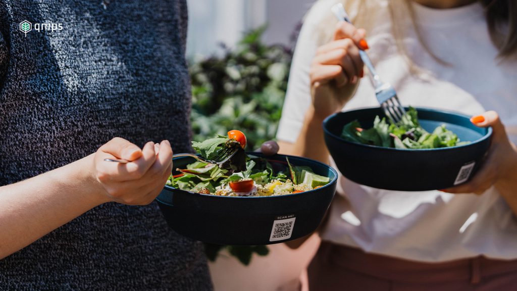 Zwei Personen halten einen Salat in einer Mehrweg-Schüssel